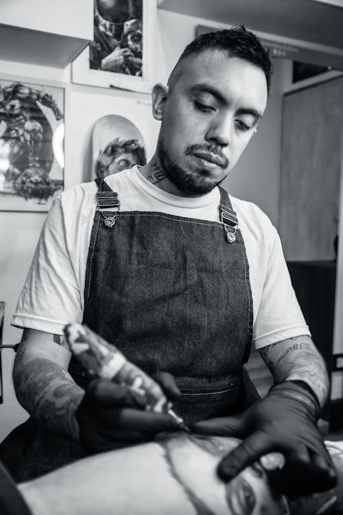Black and White Photograph of a Man Tattooing