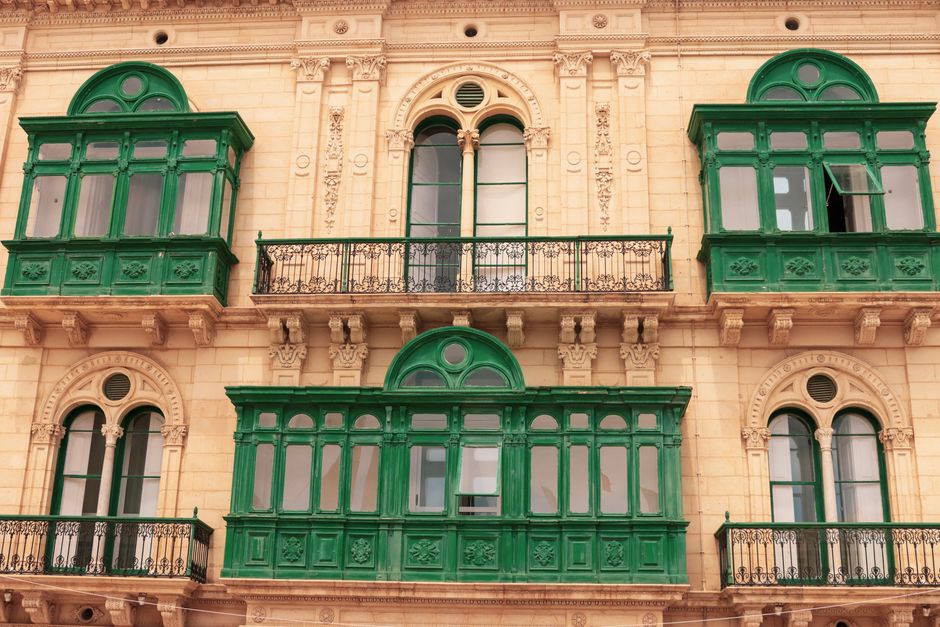 Captivating facade featuring green balconies and ornate Renaissance architecture in Valletta, Malta.