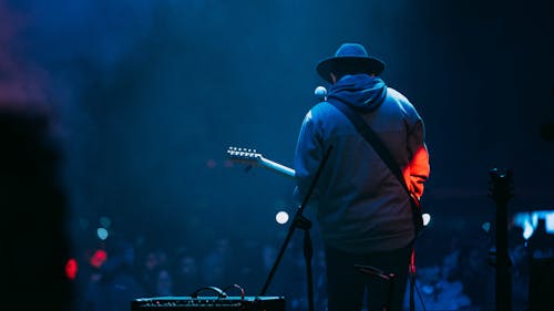 A man in a hat playing guitar on stage