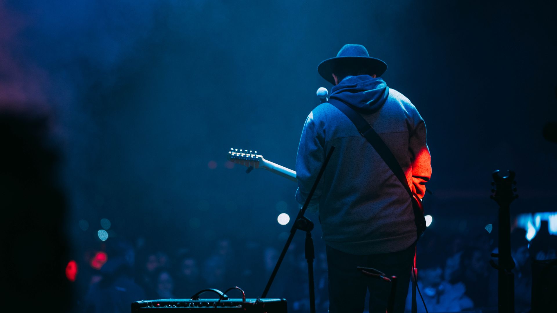 Modafinil for Musicians on Tour: Maximising Energy and Focus A musician with a hat plays guitar on a dimly lit stage at a concert — modafinil for musicians on tour