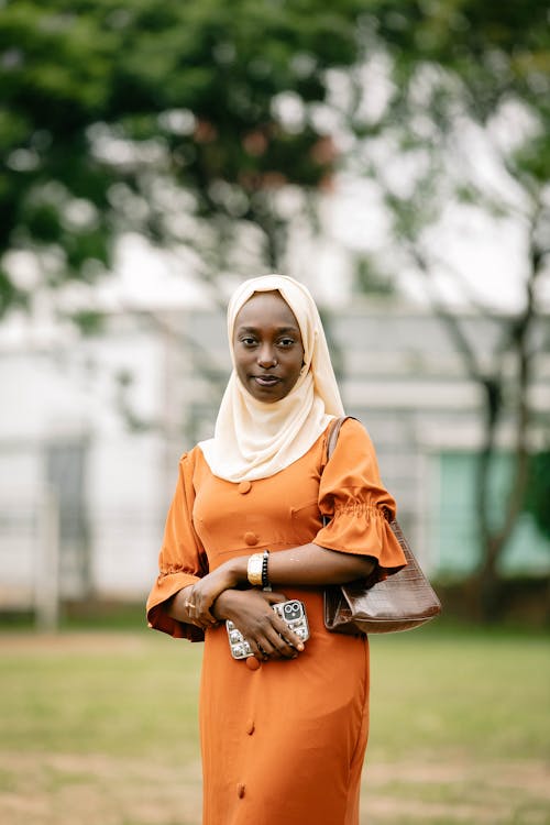 A woman in an orange dress and headscarf