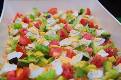 A tray of salad with tomatoes, eggs and avocado
