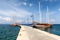 Sailboats moored at a scenic pier in Kos, Greece under a bright summer sky.
