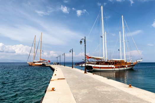 Sailboats moored at a scenic pier in Kos, Greece under a bright summer sky.