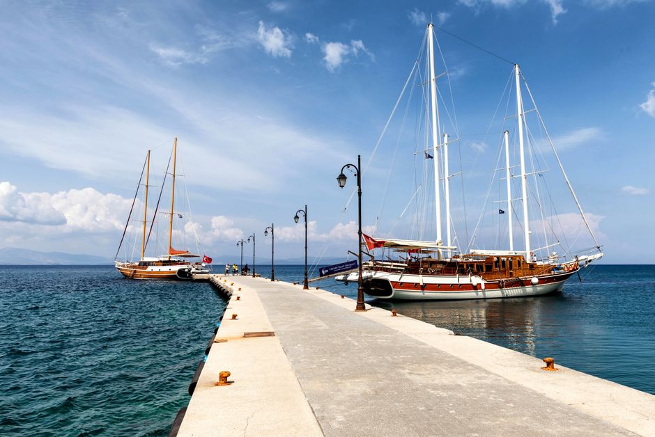 Sailboats moored at a scenic pier in Kos, Greece under a bright summer sky.