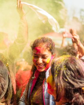 Joyful crowd celebrating Holi in India with vibrant colors and smiles outdoors.