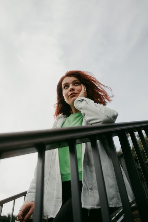 A woman with red hair standing on a railing