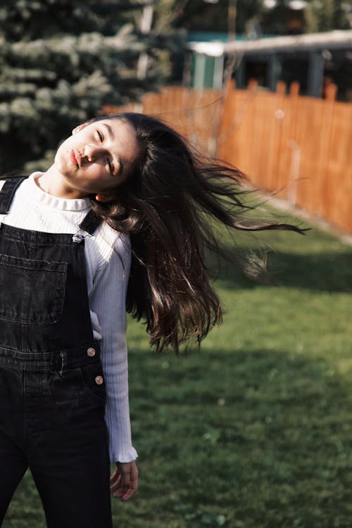 A woman in overalls standing in the grass