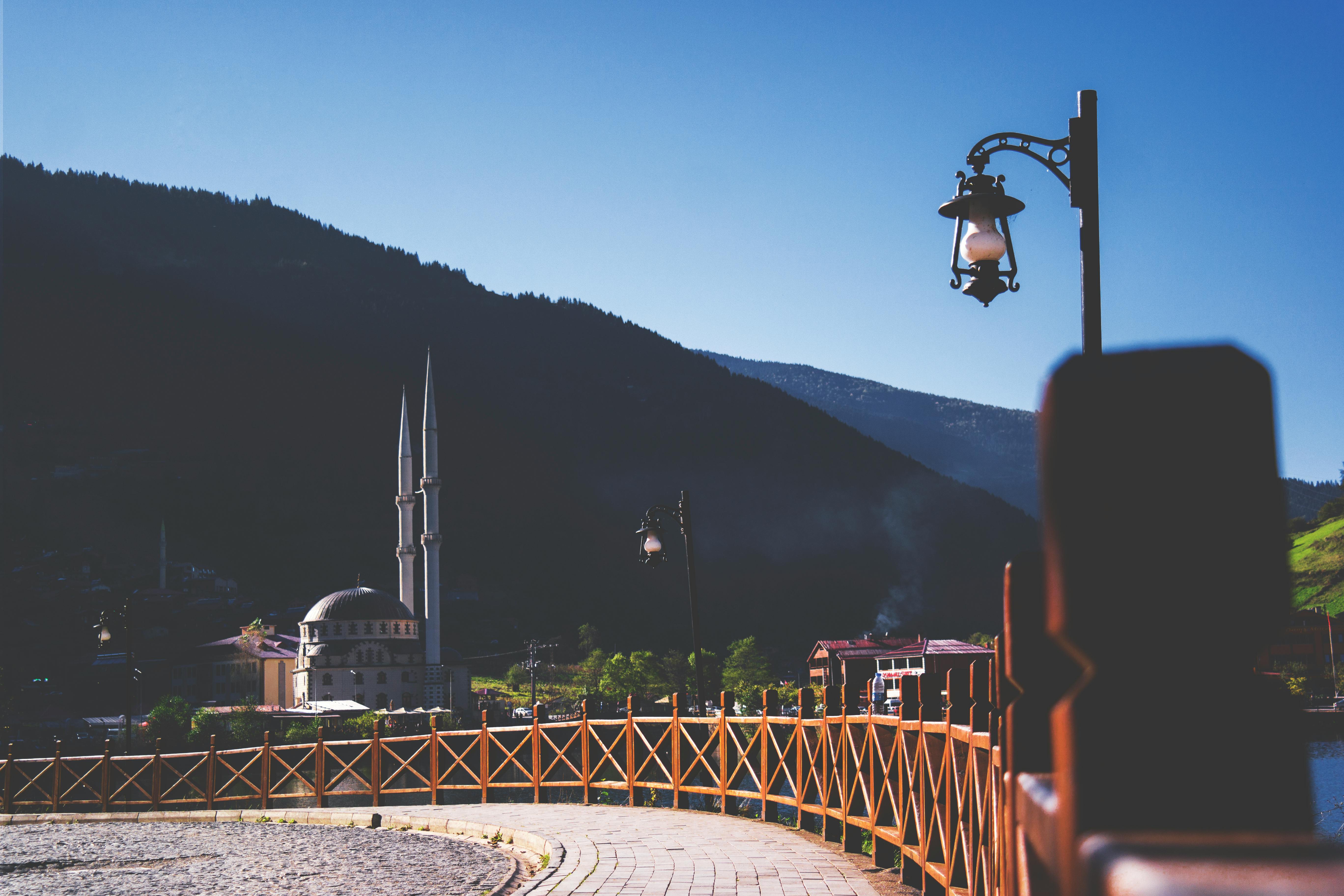 群山之中，清真寺风景如画，蔚蓝的天空下矗立着老式灯柱