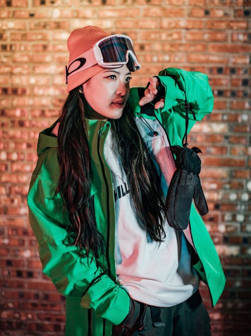A girl in a green jacket and goggles is posing