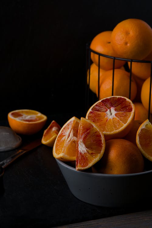 A bowl of oranges with some sliced in it