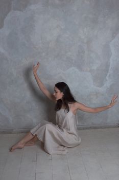 Artistic portrait of a woman in a minimalist setting, wearing a neutral-toned dress.