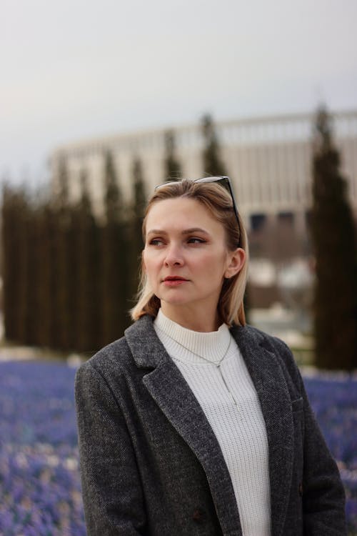 A woman in a suit and tie standing in front of a field of flowers