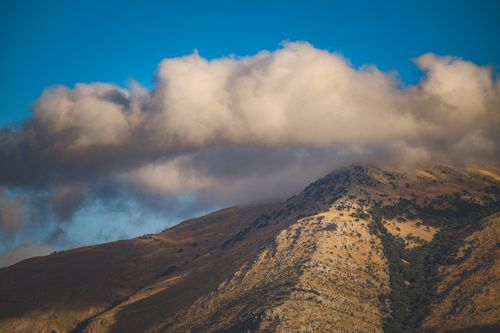 Free A striking view of clouds hovering above a rugged mountain landscape, capturing nature's raw beauty. Stock Photo