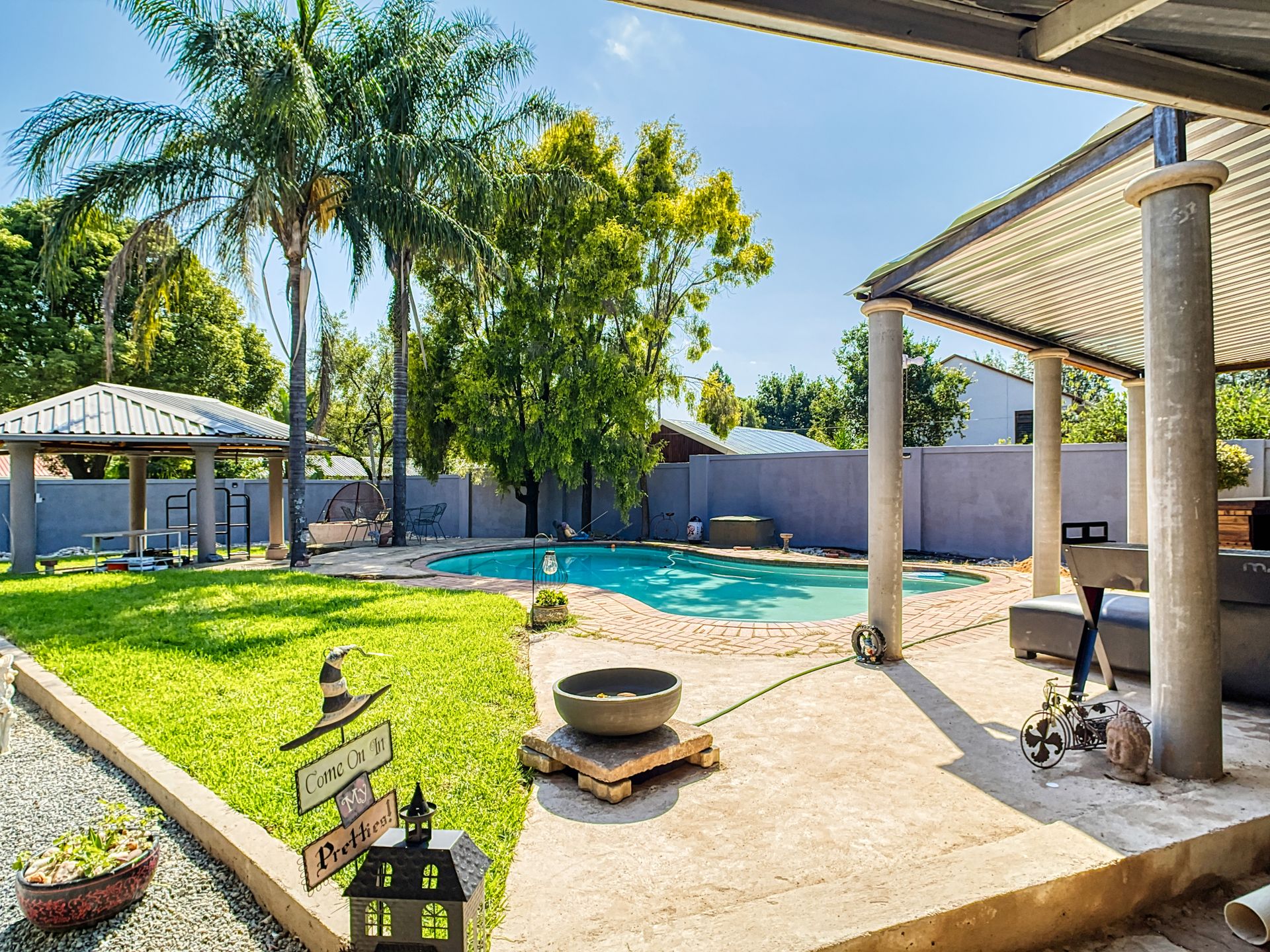 Elegant garden with pool in Pretoria, South Africa, featuring palm trees and modern outdoor furniture.