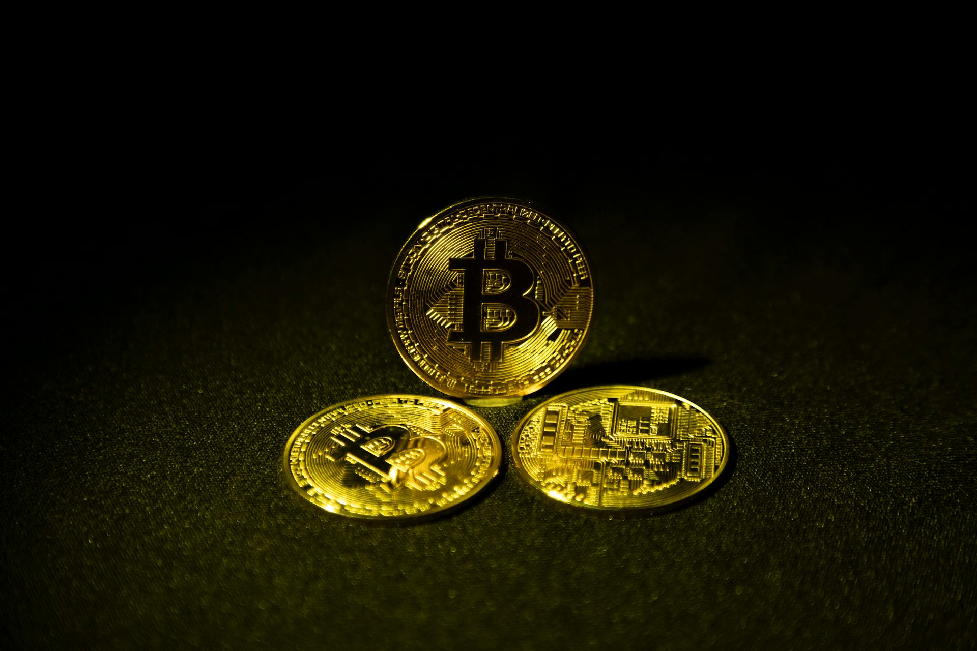 Three Gold Bitcoins on a Black Background