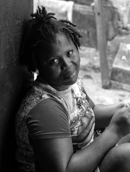 Woman in T-shirt Sitting by Wall