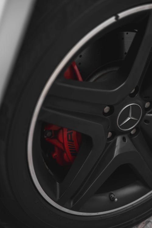 The front wheel of a mercedes benz car with red brake calipers