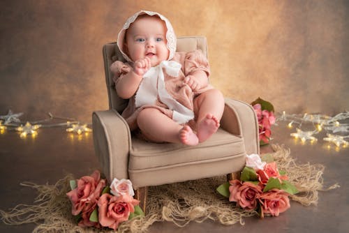 A baby girl sitting in a chair with flowers