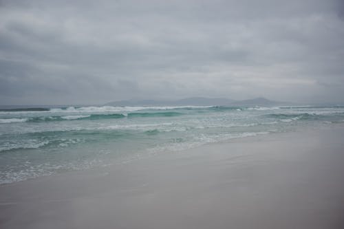 A beach with waves and a cloudy sky
