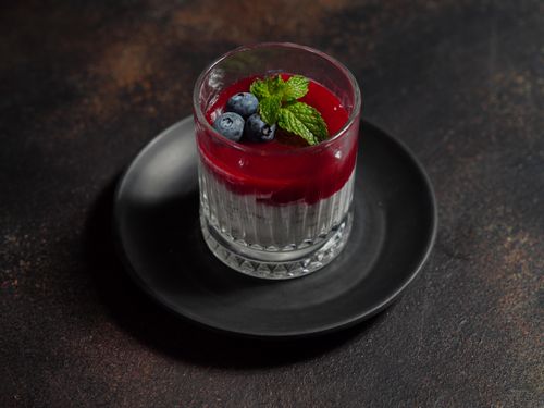 Free Elegant dessert glass on plate with blueberry and mint topping. Perfect for gourmet food presentations. Stock Photo