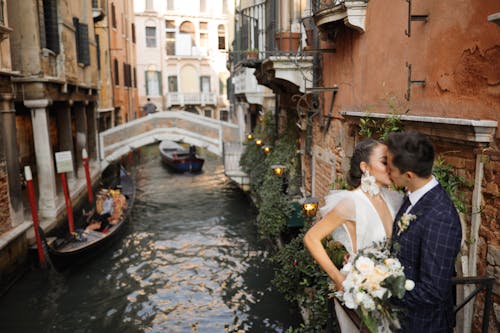 A bride and groom kiss in front of a canal