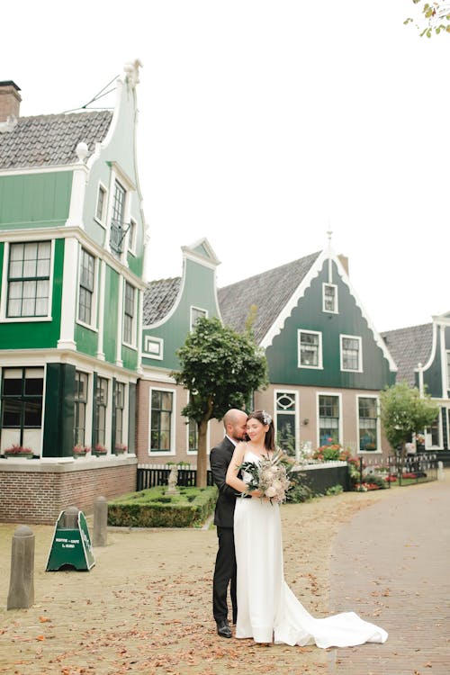 A bride and groom standing in front of a row of houses