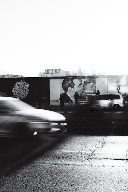 A black and white photo of a car driving by a billboard