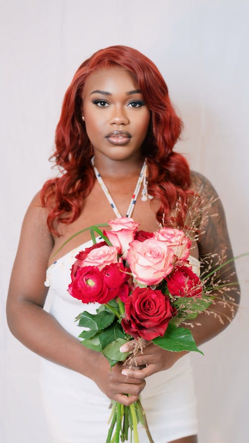 A woman with red hair holding a bouquet of flowers