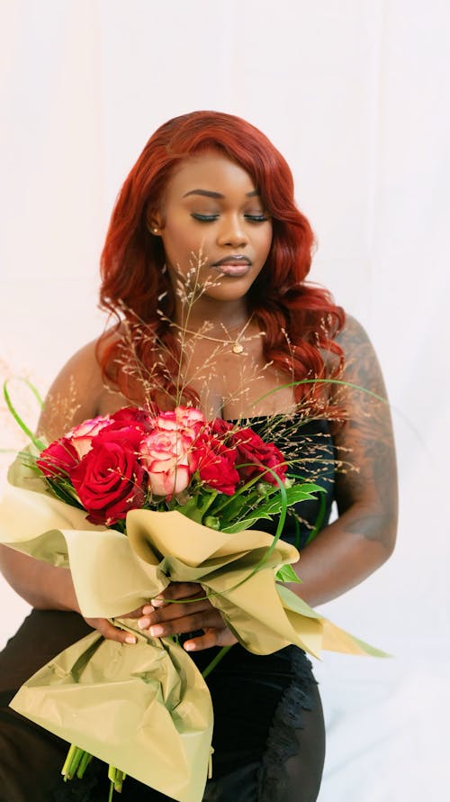 A woman with red hair holding a bouquet of flowers
