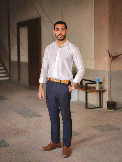 A man in a white shirt and blue pants standing in an empty room