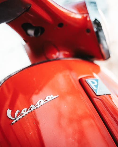 A close up of the logo on the side of a red vespa