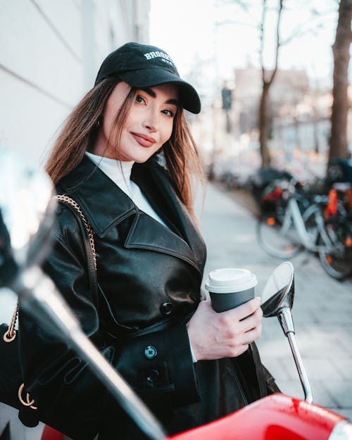 A woman in a black jacket holding a coffee cup