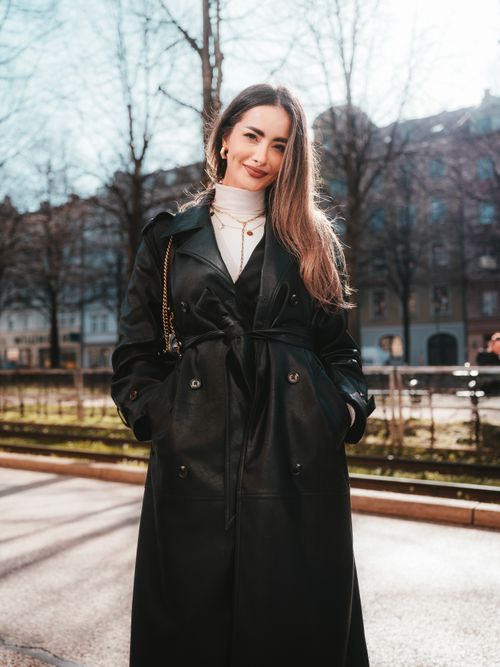 Free Woman posing outdoors in a fashionable leather coat with a bright smile in autumn sunlight. Stock Photo