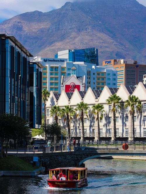 Free Colorful boat on a canal with modern buildings and mountains in Cape Town. Stock Photo