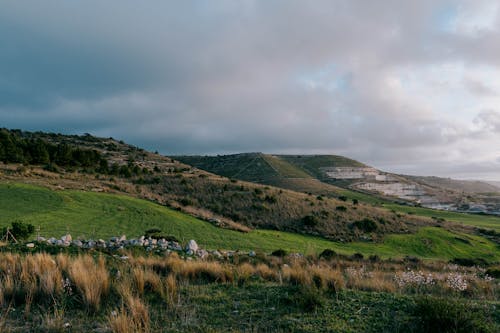 A grassy hillside with a green field and a hill in the distance