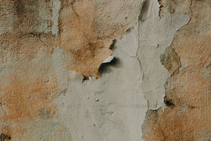 Peeling and blown plaster on a wall surface