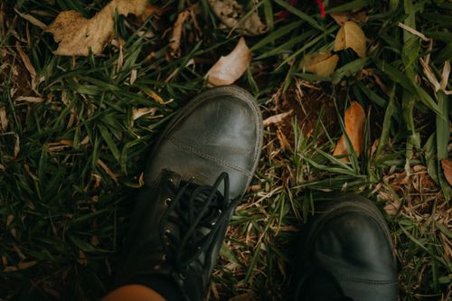 Free Close-up of leather boots standing on grass with autumn leaves. Stock Photo