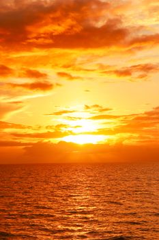 Stunning golden sunset reflecting on calm ocean waves, creating a peaceful and warm atmosphere.