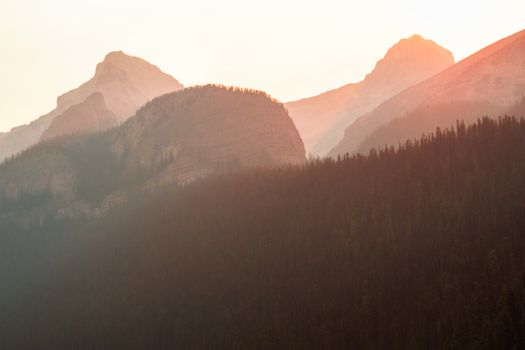 A tranquil view of sunlit mountains and forests at dusk, highlighting nature's beauty.
