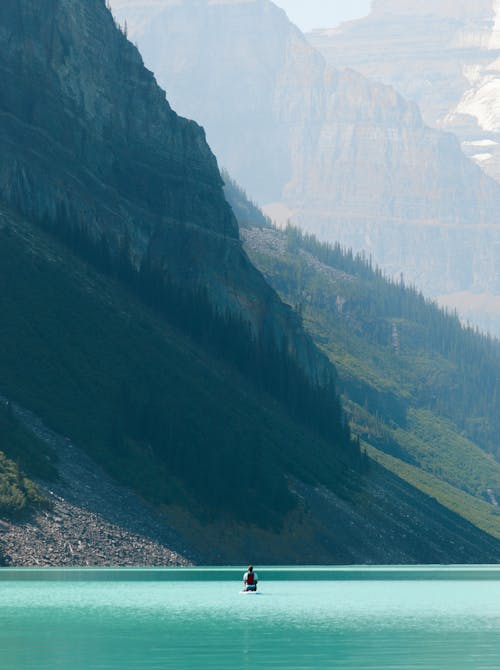 Free A man is standing on a boat in the middle of a lake Stock Photo