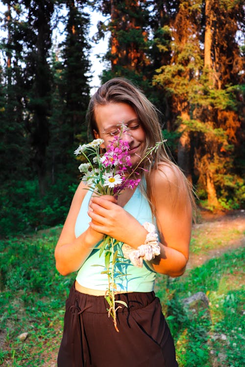 A woman is holding flowers in the woods