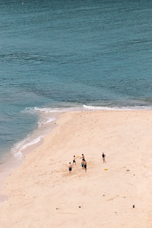 A group of people playing soccer on a beach
