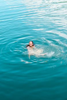 Woman swimming joyfully in clear blue water, capturing a sense of summer relaxation.