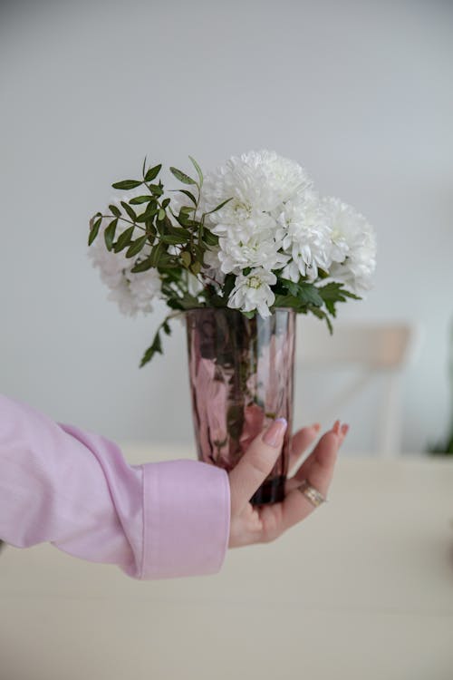 A person holding a vase with white flowers