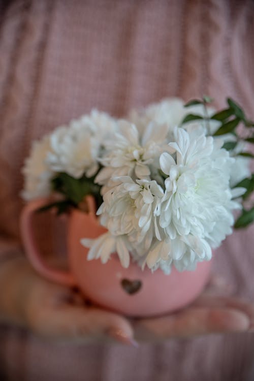 A person holding a pink mug with white flowers
