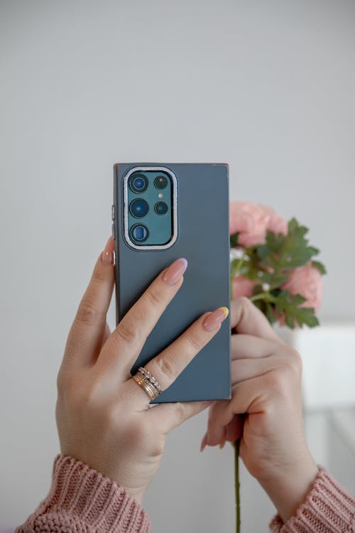 A woman holding a phone with a flower in her hand