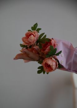 A hand beautifully adorned with pink roses in a soft, artistic setting.