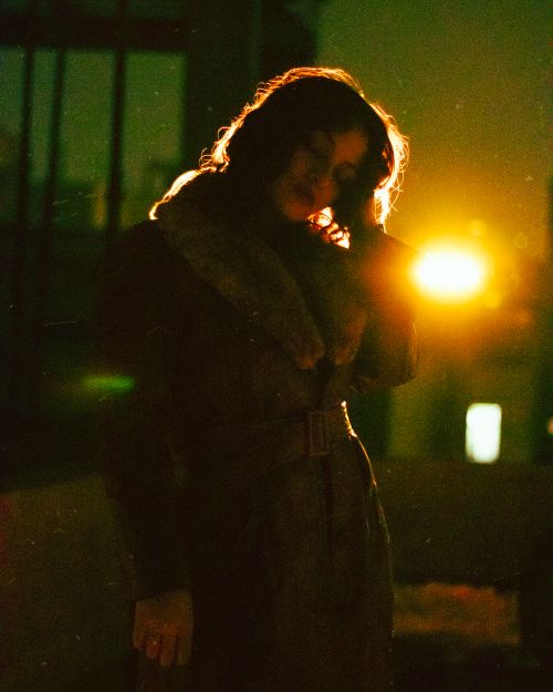 Free Silhouetted woman in coat illuminated by streetlight on a city street at night. Stock Photo