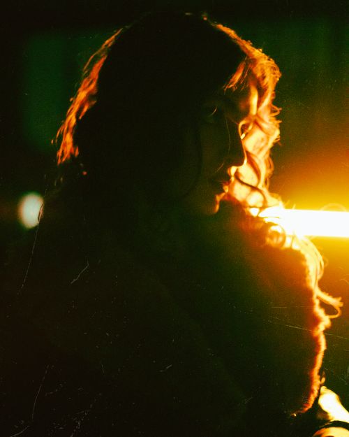 Free Artistic portrait featuring a woman in dramatic, low-light setting with moody tones. Stock Photo